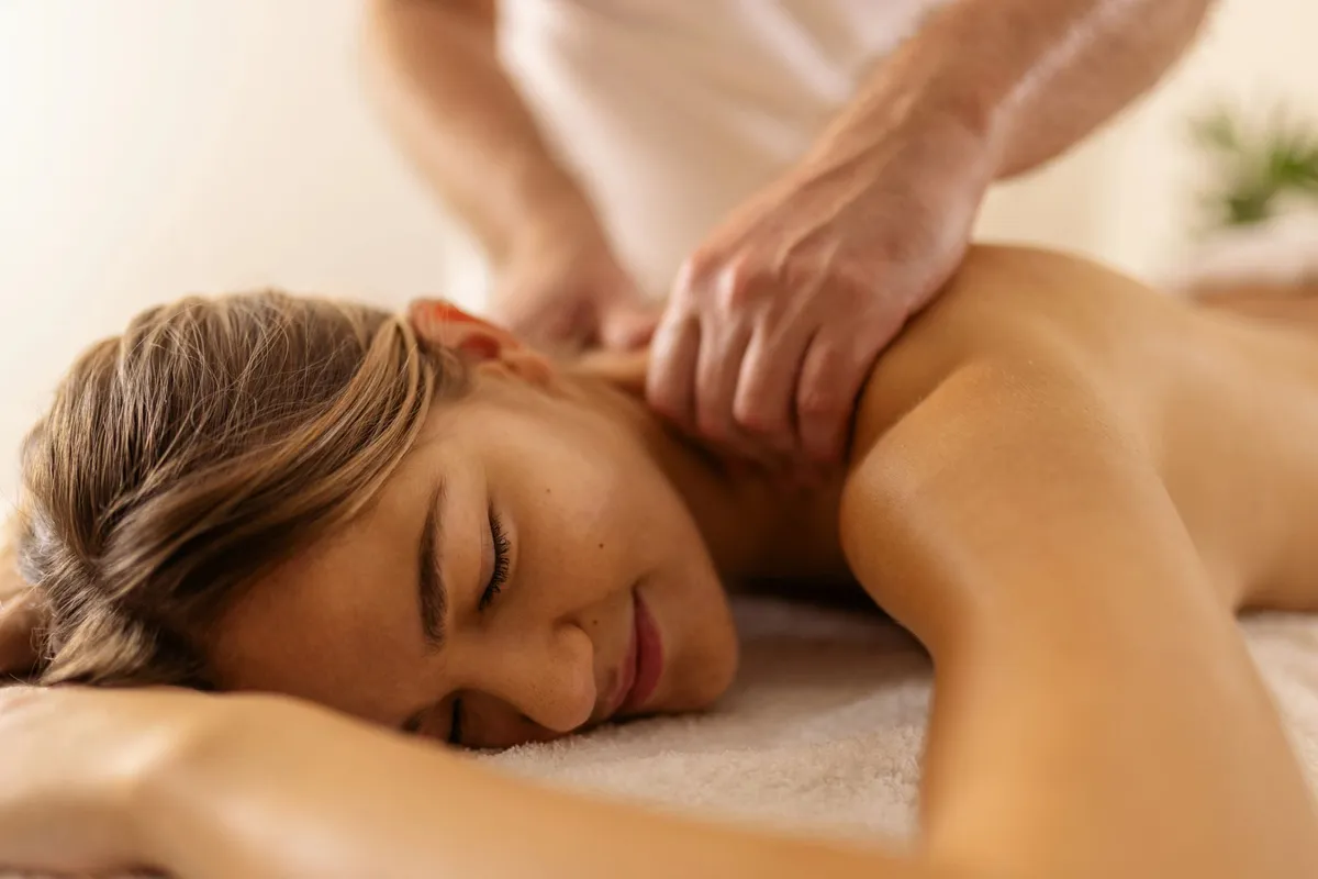 A therapist working with both hands along a client's upper back during a deep tissue massage