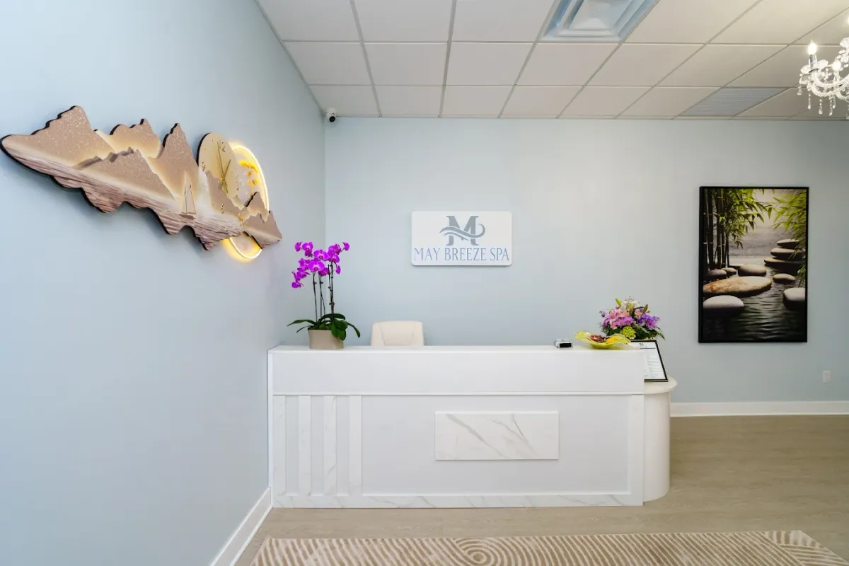 The May Breeze Spa reception desk, with the studio's logo on the wall and orchids on the counter